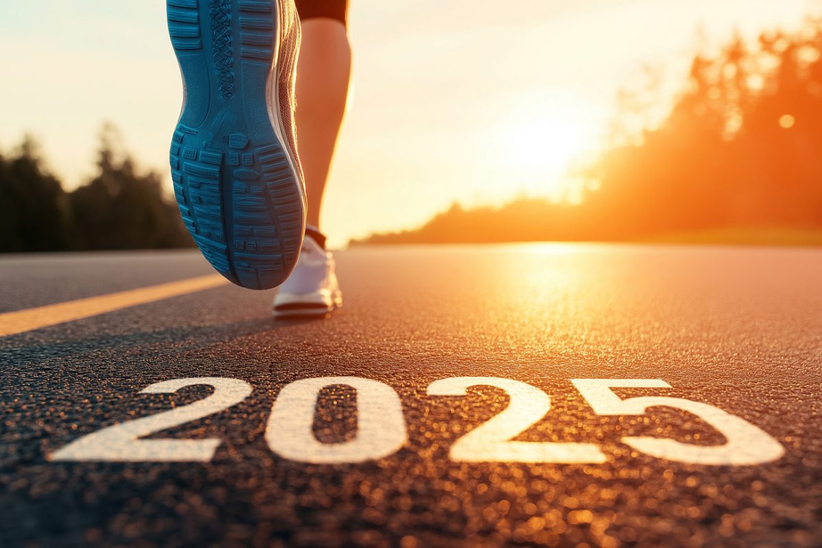 Juoksijan jalka tiellä, johon on kirjoitettu vuosiluku 2025 ja taustalla auringonlasku.