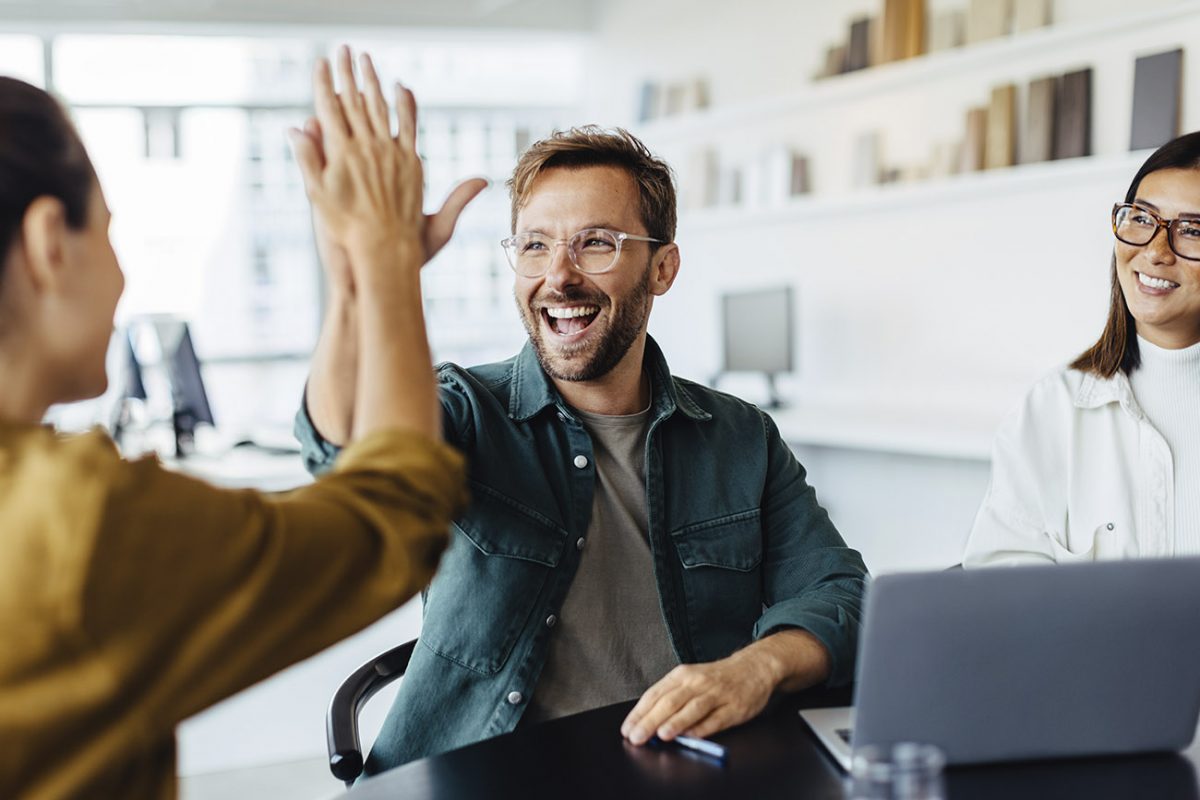 Tiimi heittää yläfemman ja iloitsee onnistumisista yhdessä toimistolla.