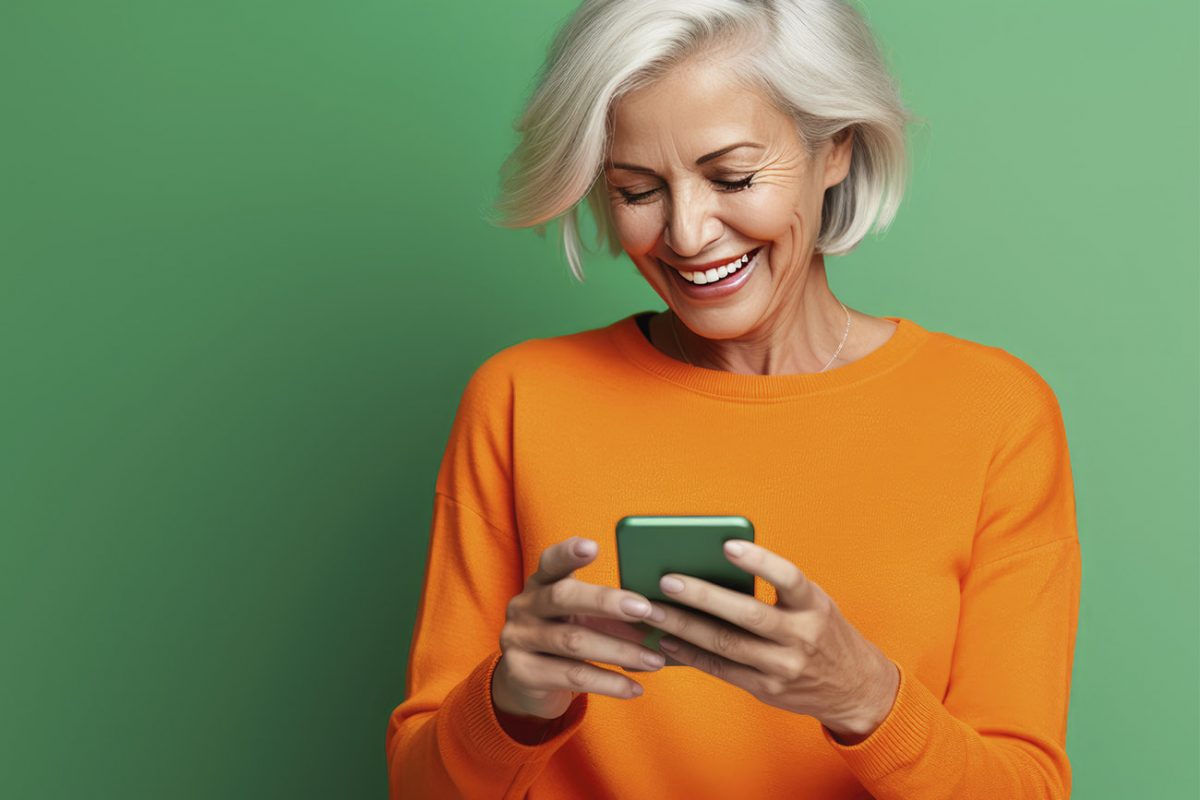 Nainen katsoo kännykän näytölle ja hymyilee.