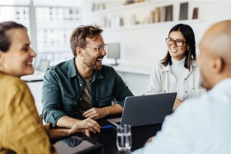 Tiimi keskustelee innoissaan toimistolla yhteisen pöydän äärellä.