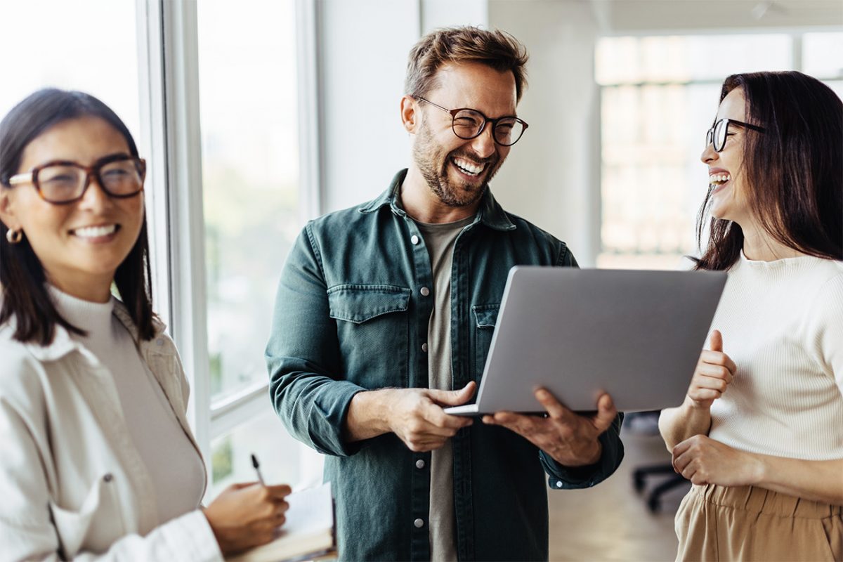 Tiimi keskustelee iloisena toimistolla.