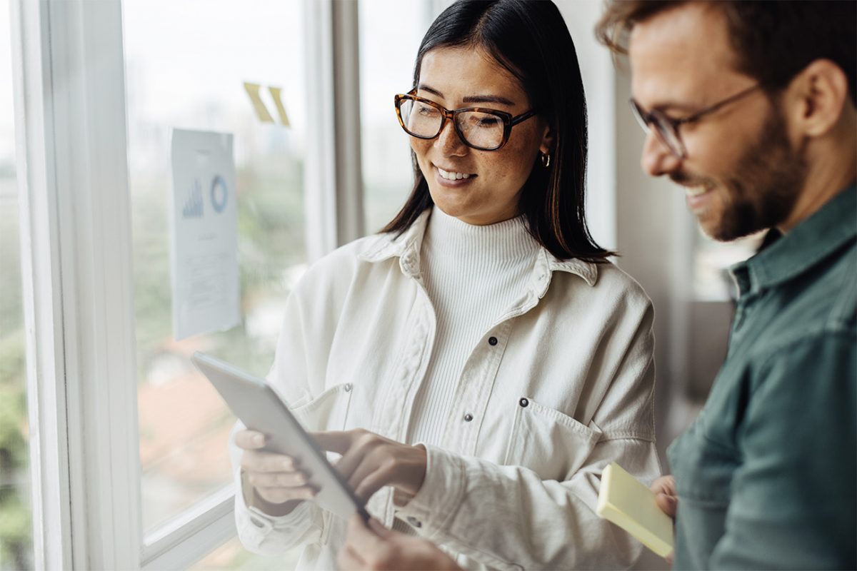 Kollegat juttelevat ja tarkastelevat tabletin näyttöä.
