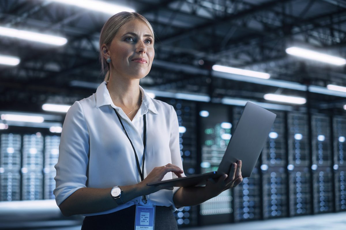 Nainen kannettava tietokone kädessään konesalissa.