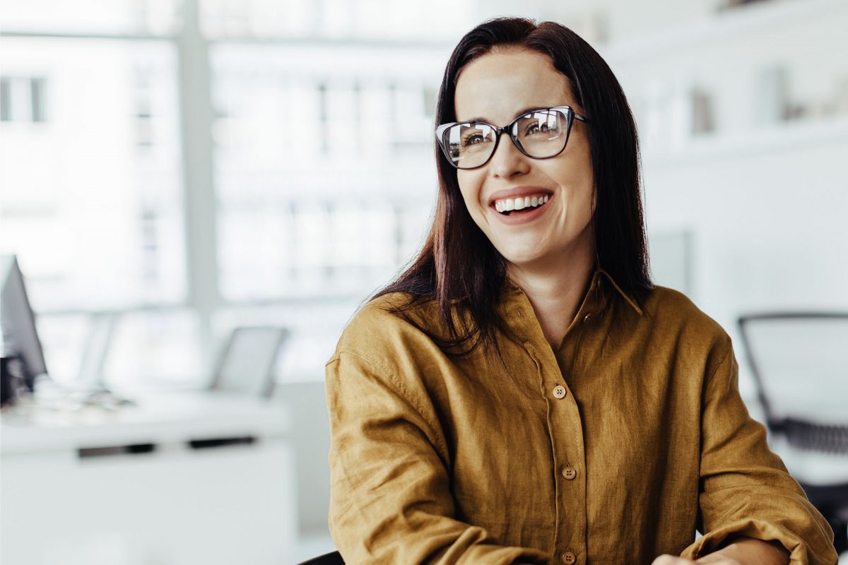 Nainen tyytyväisenä töissä toimistolla. 
