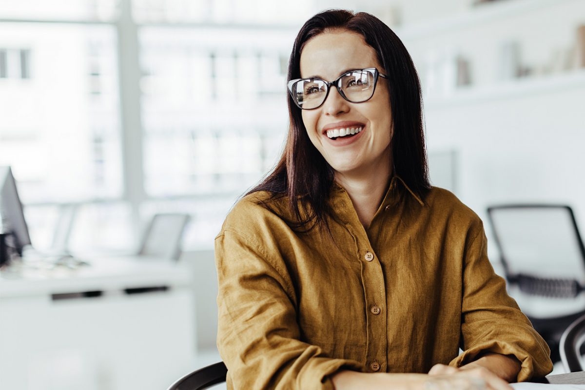 Nainen tyytyväisenä töissä toimistolla.