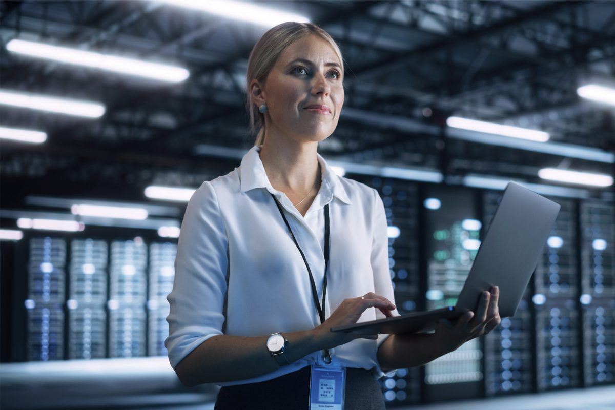 Nainen kannettava tietokone kädessään konesalissa.